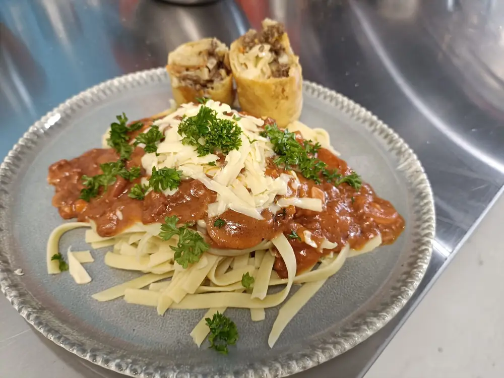 Pasta served with sauce, grated cheese and herbs