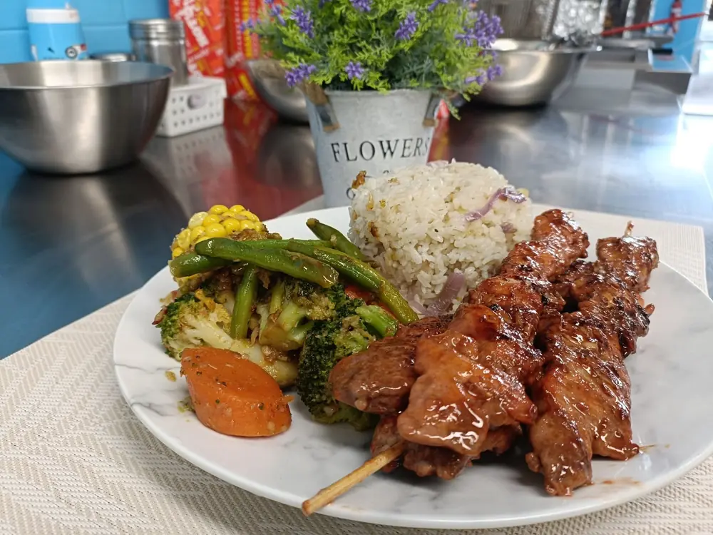 Chicken skewers served with rice and mixed vegetables